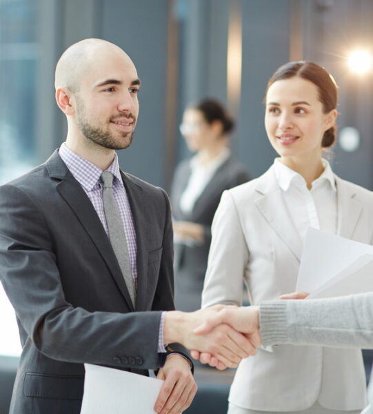 Two business professionals shaking hands after discussion of contract terms