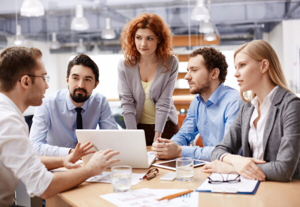 Group of business partners listening to colleague at meeting